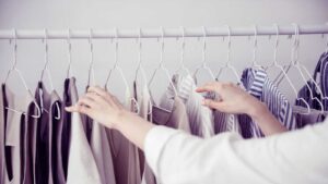 woman looking through rack of hanging clothes