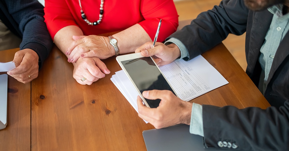 person in black suit holding white digital tablet over table